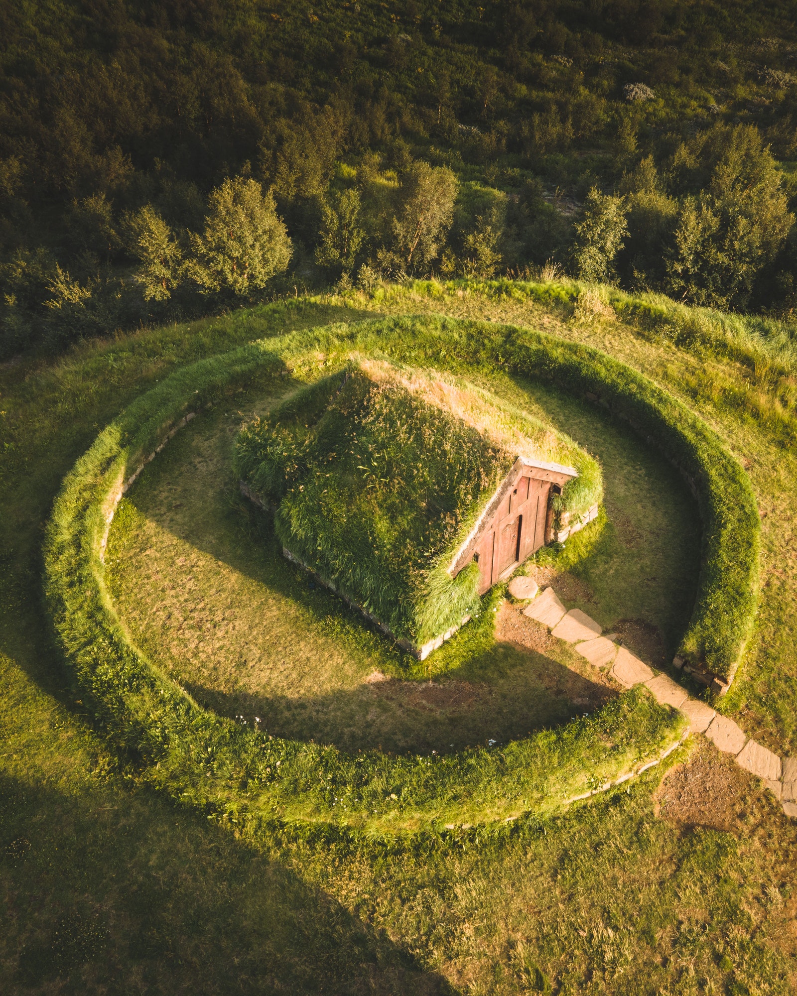 Aerial shot of circle shape grass with an old cabin covered with grass