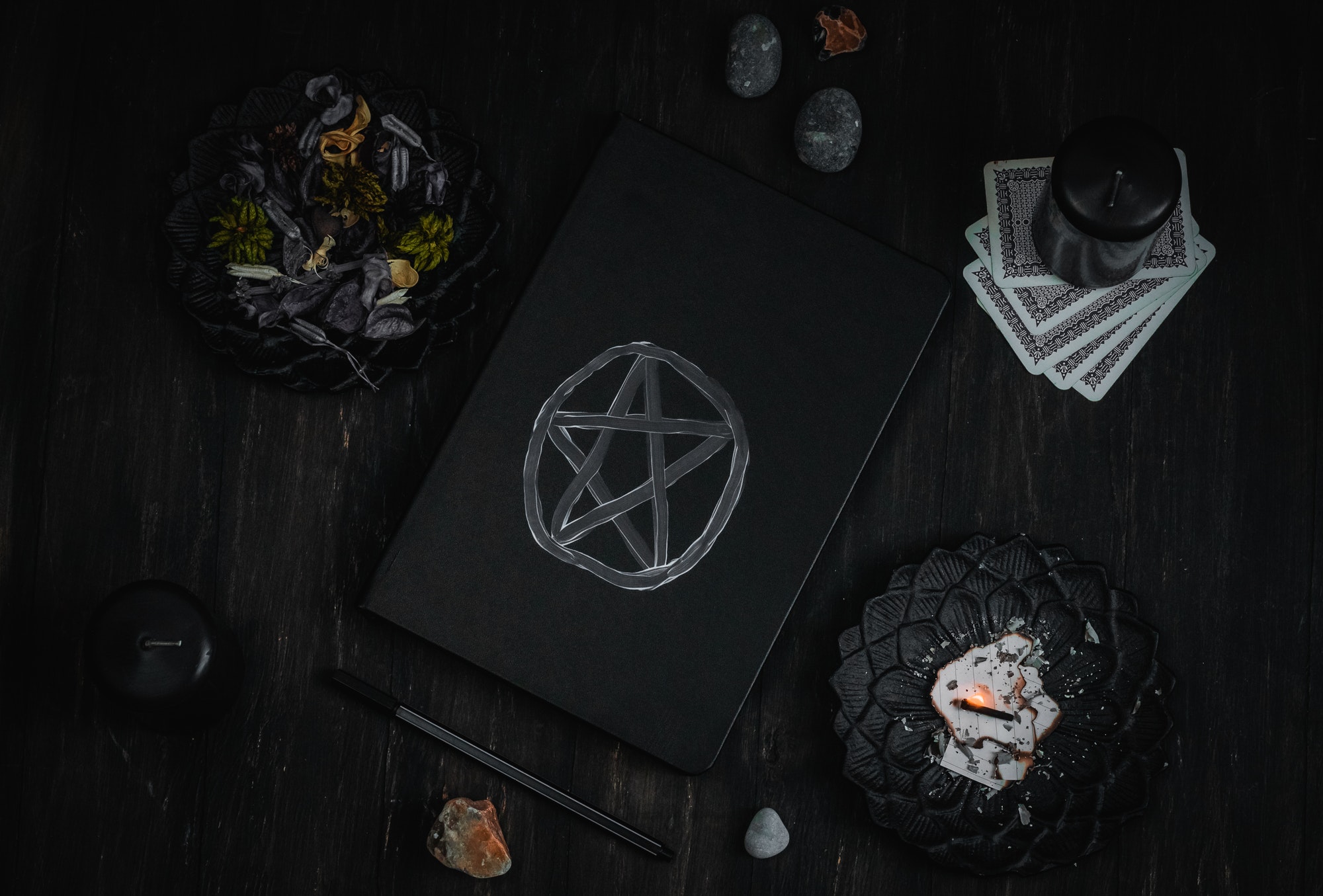 Black book, ritual stones, candles, dried flowers and tarot cards