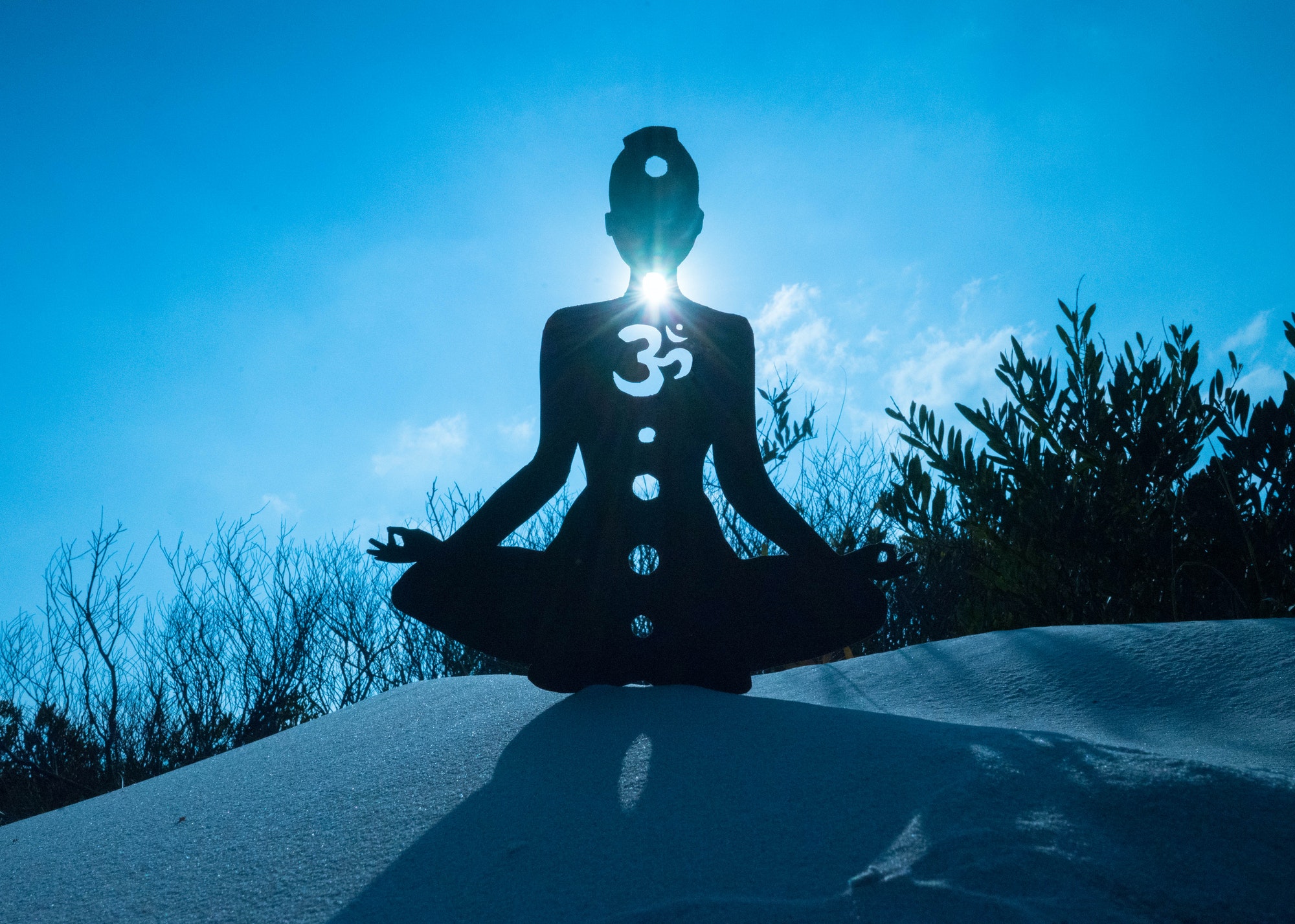 Silhouette of a person doing yoga with the root chakra symbol